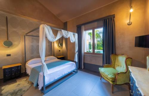 a bedroom with a canopy bed and a chair at Aqua Venere Pool & Suites in Marsala