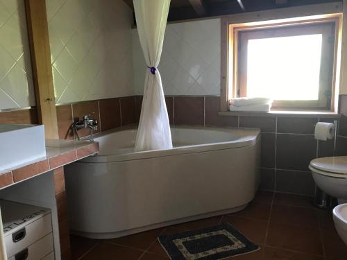 baño con bañera, aseo y ventana en B&B Casa Del Viandante en Colico