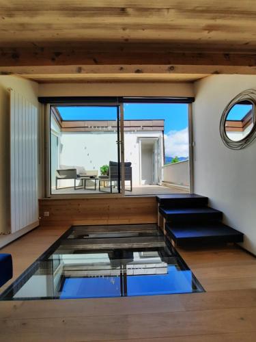 - un salon avec un sol en verre et une grande fenêtre dans l'établissement PLUS PRES DES ETOILES, à Annecy