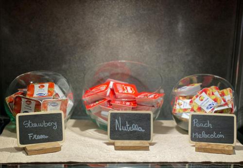three bowls of candy on a table with labels at SM Hotel Sant Antoni in Barcelona