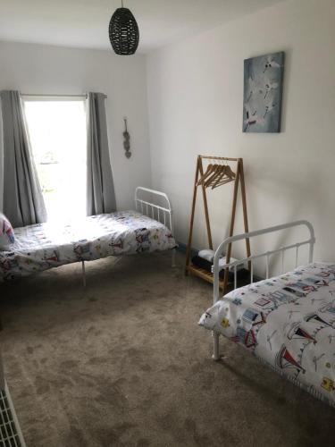 um quarto com 2 camas e uma janela em Graigfryn em Amlwch