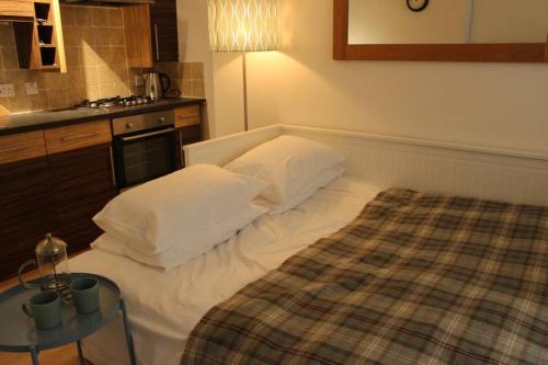 The Snug, a great flat in the heart of Peebles. في بيبلز: غرفة نوم صغيرة مع سرير وطاولة