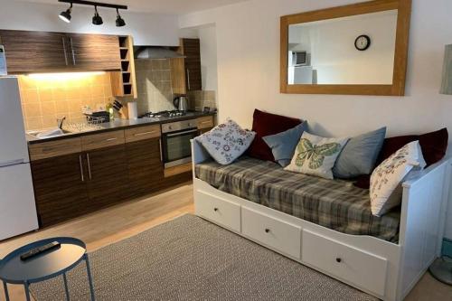 a living room with a couch and a kitchen at The Snug, a great flat in the heart of Peebles. in Peebles