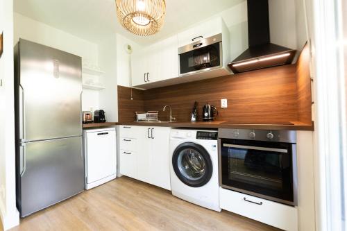 une cuisine avec un lave-linge et un réfrigérateur dans l'établissement Suite Tropical Disneyland Paris - Jardin privé !, à Montévrain