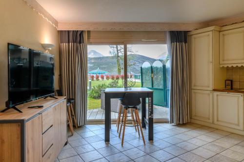 uma cozinha com uma mesa, uma televisão e uma janela em Rare : au bord du lac d’Annecy, cosy appartement en rez de jardin avec terrasse privative em Duingt