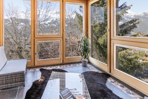 a living room with large windows and a table at Chalet Steingärtli 1 in Wengen
