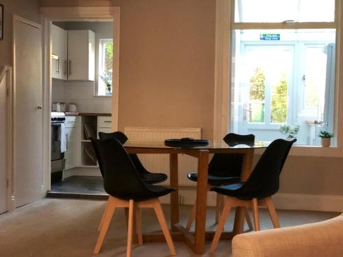 cocina con mesa, sillas y ventana en Radford Place - Central Exeter - Patio & Garden - Beach - Chiefs - Uni -WiFi, en Exeter