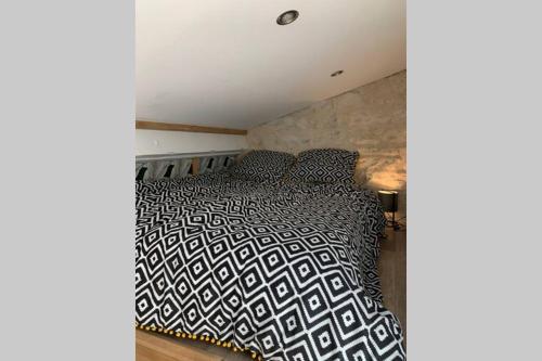 a bedroom with a bed with a black and white comforter at Maison proche centre-ville in Dijon