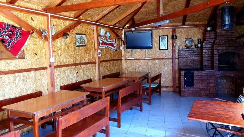a restaurant with wooden tables and a tv on the wall at La Podul Gornii in Gornea