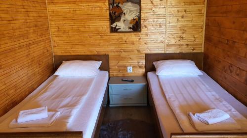 two beds in a room with wooden walls at La Podul Gornii in Gornea