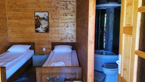 two beds in a small room with a shower at La Podul Gornii in Gornea