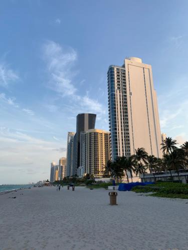einen Sandstrand mit hohen Gebäuden im Hintergrund in der Unterkunft Walk to the Beach at Sunny Isles in Miami Beach