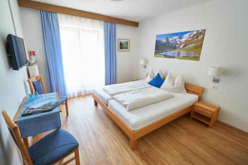 a bedroom with a bed and a desk and a television at Privatpension Bergkristall in San Martino