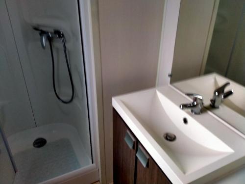 La salle de bains est pourvue d'un lavabo et d'une douche. dans l'établissement MOBIL HOME Climatisé 6 Personnes au Camping Marvilla Parks - Le Parc Des Septs Fonts, à Agde