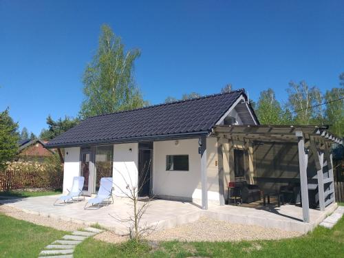 a white shed with chairs and a patio at Mazury domek całoroczny Pelnik gm Ostróda jezioro las in Pelnik