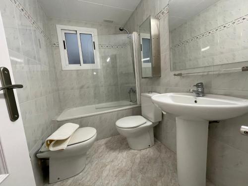 a white bathroom with a sink and a toilet at Apartamento para 7 personas en Calafell, Barcelona. in Calafell