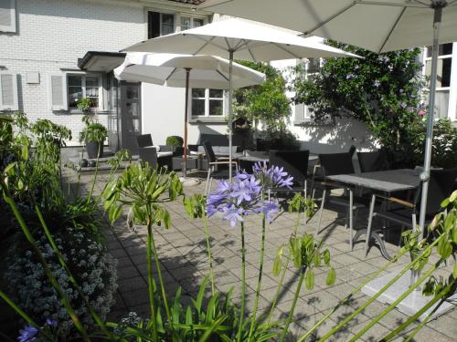 a patio with tables and umbrellas and purple flowers at Landgasthaus Bären in Grub