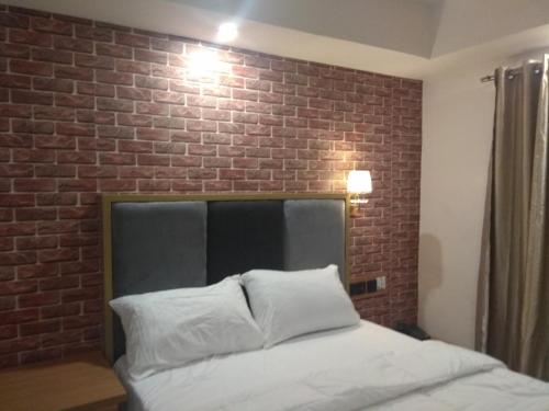 a bedroom with a brick wall and a bed at Shamrockmanor(TheResidence) in Benin City
