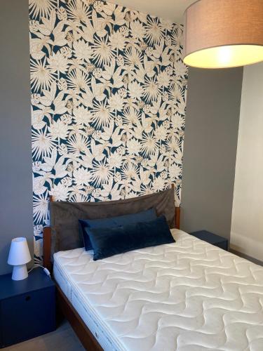 - une chambre avec un lit blanc et un papier peint floral dans l'établissement Le grand briochin, à Saint-Brieuc