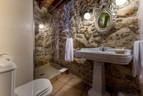 y baño de piedra con lavabo y ducha. en El Patio de Valentina, en Navacerrada