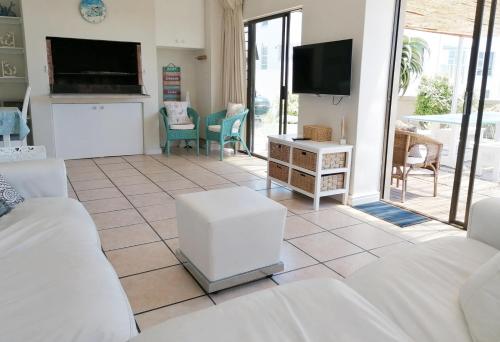 a living room with white furniture and a flat screen tv at Orca View Melkbosstrand in Melkbosstrand