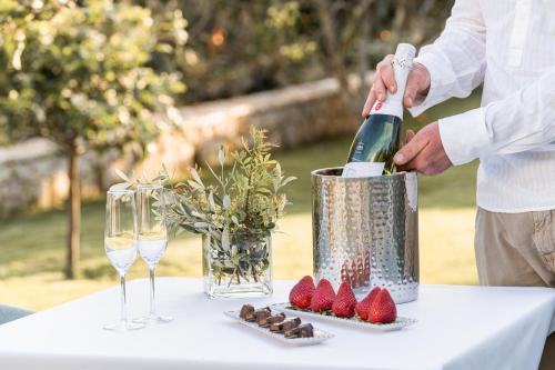 a man pouring a bottle of wine on a table with strawberries at Agroturismo Malbuger Nou Menorca -Adults only- in Mahón