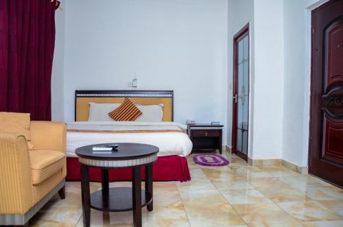 une chambre avec un lit, une chaise et une table dans l'établissement Nuoyong Empire Hotel, à Wa
