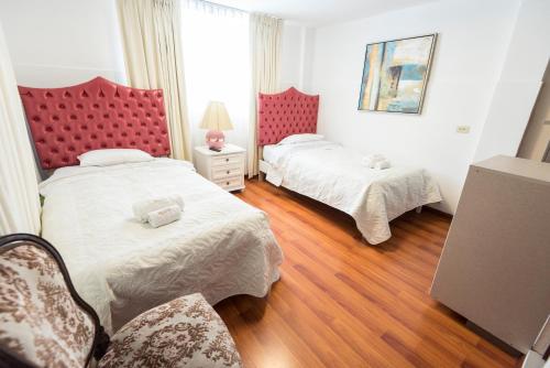 a bedroom with two beds and a red headboard at INTI KILLA Hostel in Lima