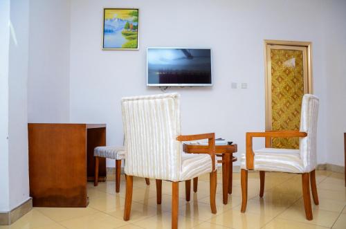 a room with two chairs and a table and a tv at Nuoyong Empire Hotel in Wa