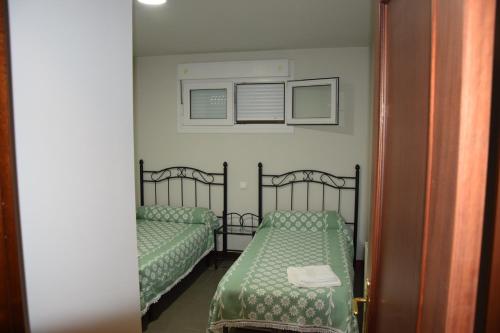 um quarto com 2 camas com lençóis verdes e um espelho em La Fuente de la Quintana em Arredondo