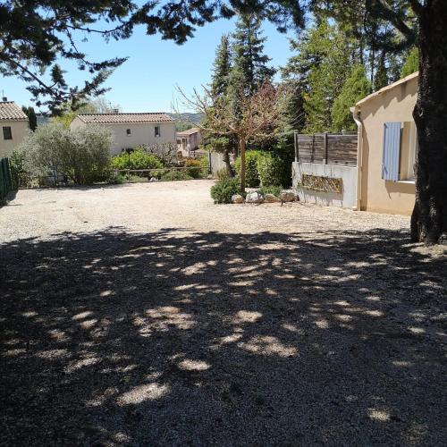 a large yard with a tree and a house at L'Arc en Ciel in Gréoux-les-Bains