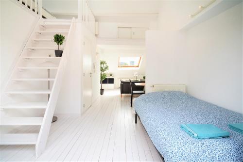 biały pokój z łóżkiem i schodami w obiekcie Beautiful Cozy Cityflats in the Centre of Antwerp w Antwerpii