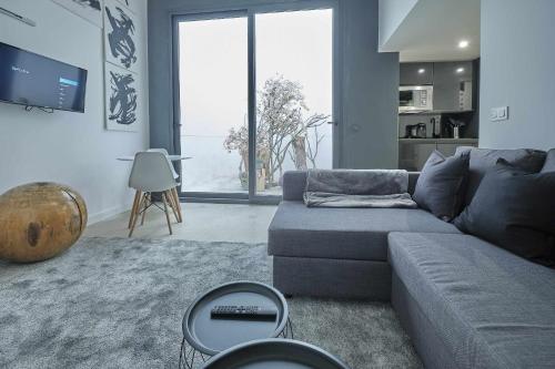 sala de estar con sofá gris y ventana grande en ALANDALUS Modern y Luxury, en Sevilla