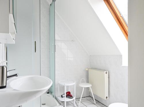 a white bathroom with a sink and two stools at Studio, Nähe Dieksee in Malente