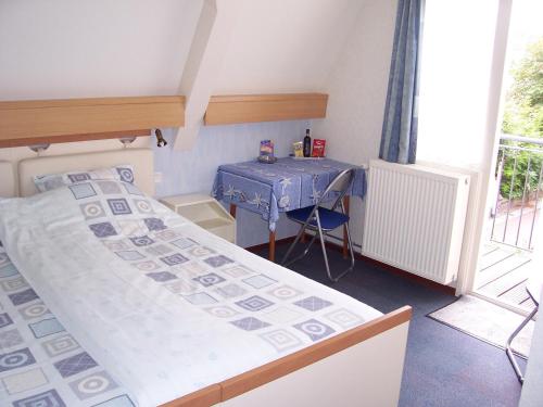 a small bedroom with a bed and a table at Hotel Arosa in Zandvoort