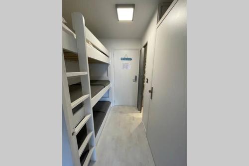 - un couloir avec des lits superposés blancs et une porte dans l'établissement APPARTEMENT LA BAULE 5 PERS A 50 M DE PLAGE, à La Baule