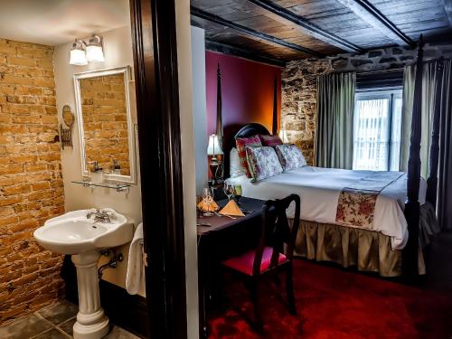 ein Bad mit einem Bett und einem Waschbecken in einem Zimmer in der Unterkunft Le Clos Saint-Louis in Québec