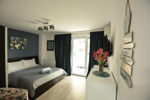 a bedroom with a bed and a vase of flowers on a table at Mario Apartamente - Romantic Mamaia in Mamaia