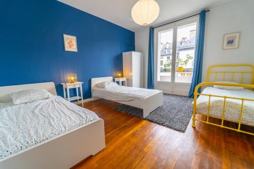 Un dormitorio con dos camas y una pared azul. en Tours Hyper Centre - Balcon - Arrivée autonome, en Tours