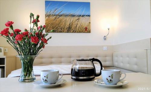 a table with two cups and a vase with flowers at Dom Gościnny Harpun in Władysławowo