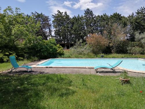 una piscina con 2 sillas en el césped en Studio entre Nimes et Uzes, en Lédenon