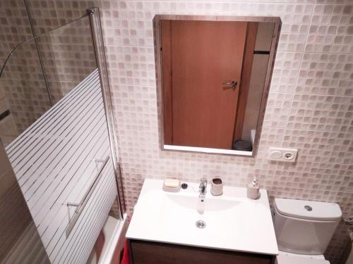 Un baño con lavabo, inodoro y espejo. en APARTAMENTO KENITRA, en Avilés