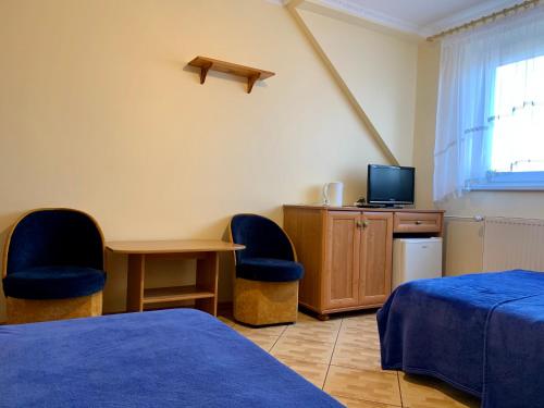 Habitación con 2 camas, mesa y TV. en Pokoje Gościnne ADRIAN en Krynica Morska
