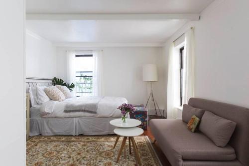 a bedroom with a bed and a couch and a table at Cozy bright studio - Soho/Greenwich Village - 30+Days Only in New York