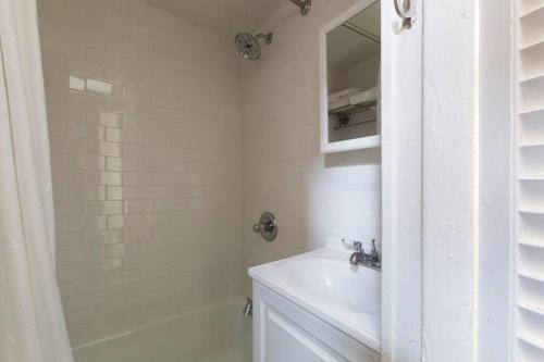 Baño blanco con lavabo y espejo en Cozy bright studio - Soho/Greenwich Village - 30+Days Only, en Nueva York