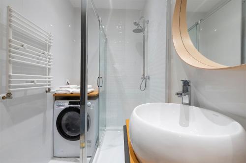 Un baño con lavadora y lavabo. en MYE Apartments - Ilumino, en Łódź