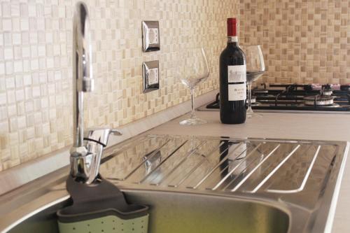 a kitchen sink with a bottle of wine and wine glasses at Casa Colapesce in Messina