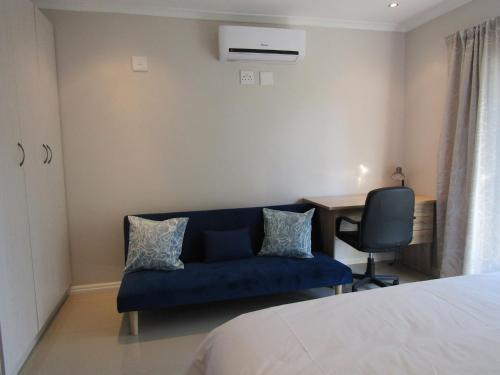 una camera da letto con divano blu e scrivania di Pafuri Gate Guesthouse a Mabalingwe Game Reserve