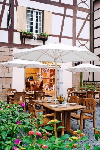a patio with tables and chairs with umbrellas at Colmar Tropicale in Bukit Tinggi