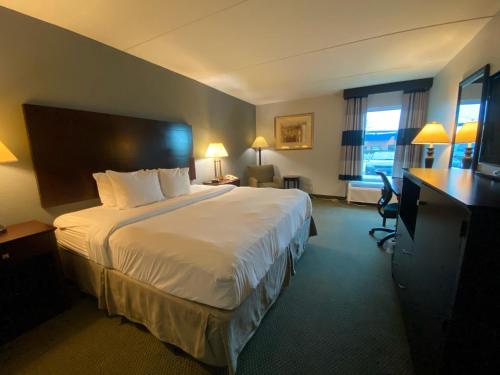 Una habitación de hotel con una cama grande y un escritorio. en Ramada by Wyndham Luling, en Luling